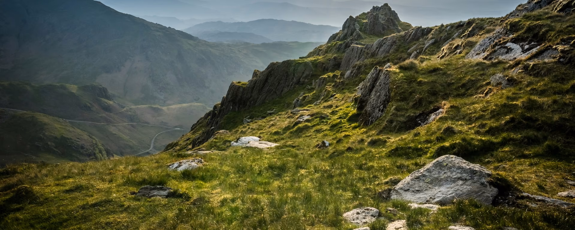 Rocky Lakeland ridge and grassy slope looking over layered hills