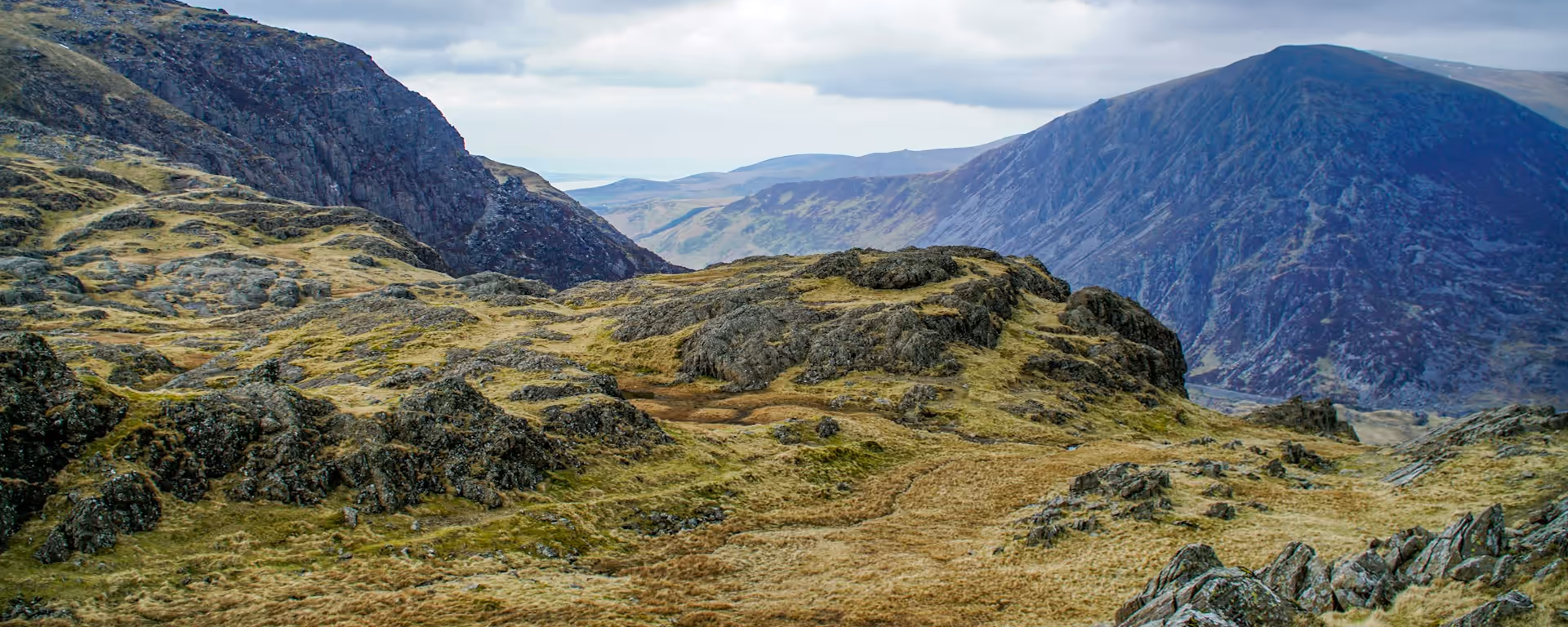 Tawny rocky ridge looking over a mountain pass under cloud